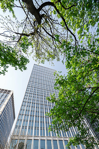 Exterior view of the Marienturm mixed-use tower block in Frankfurt with a tree in front of it.