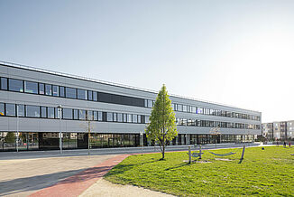 Part of the Seestadt Aspern campus in Vienna with a glass façade and a playground in front of the building.