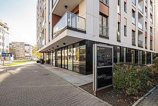 Corner view of the lower floors of the Piano House residential building directly on a street in Warsaw.