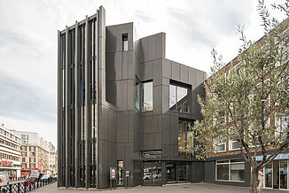 Exterior view of the modern Léo Délibes music school with its black façade, many windows and entrance area in Paris.