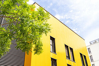 Building with yellow façade and windows in the Pôle PIXEL industrial estate in France.