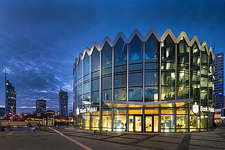 Illuminated residential and commercial buildings and Bank Polski in the Rotunda mixed-use building in Warsaw at night.