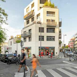 Corner view of a building in Paris with a supermarket on the ground floor and flats on the floors above.