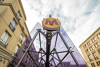 Purple coloured glass roof of a metro entrance in Warsaw between two buildings.