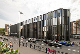 Street view of the modern Léo Délibes music school with its black façade and many windows in Paris.