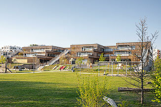 Exterior view with wooden façade and stairs leading to the terraces on the various floors of the Seestadt Aspern educational campus in Vienna.