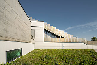 Exterior view with concrete façade and stairs to the terraces of the Seestadt Aspern educational campus in Vienna.