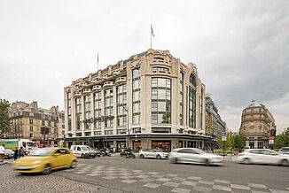 A busy street in the centre of Paris with the La Samaritaine department stores' in the background.