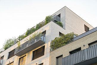 Exterior façade of a mixed-use building in Paris with balconies and roof terraces.