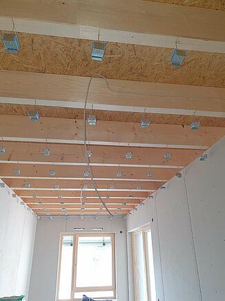 Suspended wooden beam ceiling with REGUFOAM hangers in a retirement home in Kümmersbruck.