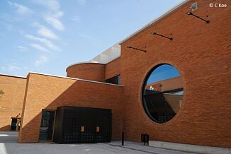 Brick building with large round glass window at the Volkstheater in Munich.