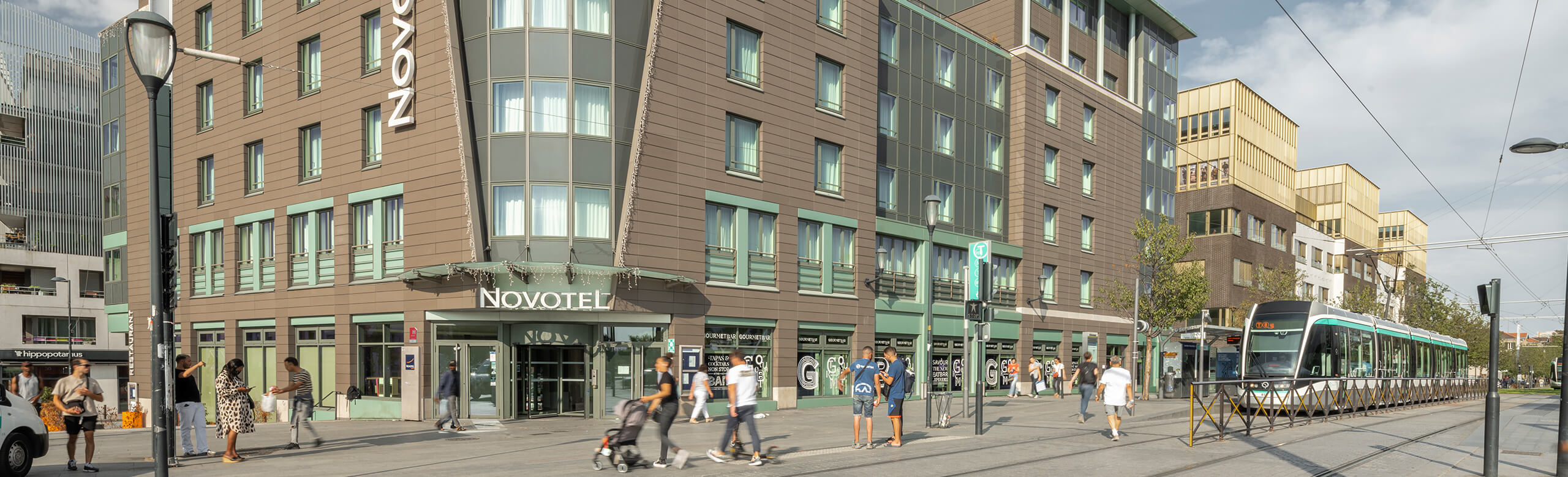 Street view of the entrance to the Novotel in Paris with the tram directly in front of the hotel.